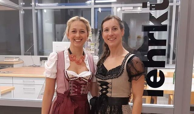 Die beiden Ernährungsberaterinnen tragen einen Dirndl und stehen einladend vor der Lehrküche.